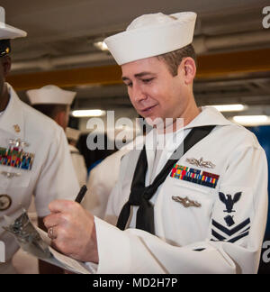 ATLANTIC OCEAN (March 26, 2018) Personnel Specialist 1st Class William E. Curtis, from Houston, Texas, annotates uniform discrepancies during a service dress white uniform inspection in the fo'c'sle aboard the aircraft carrier USS George H.W. Bush (CVN 77). The ship is underway conducting sustainment exercises to maintain carrier readiness. Stock Photo