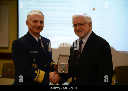 Coast Guard Rear Admiral David Throop, commander, 13th District, presents Alan Allen the Coast Guard’s Meritorious Public Service Award medal, during a meeting of the Northwest Area Contingency Plan committee meeting in Tacoma, Wash., March 28, 2018.    Allen was honored for his efforts and expertise in response to maritime environmental incidents, including having operational oversight of 376 significant in situ oil pollution burns eliminating an estimated 12.6 million gallons of oil, or 17 percent of the total estimated spilled. Stock Photo