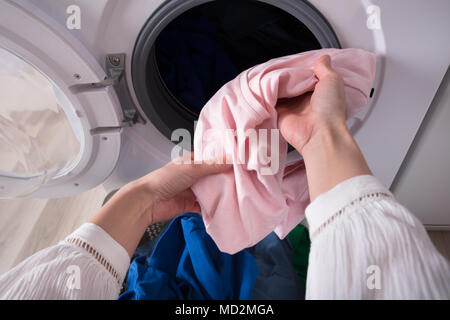 Close-up Of A Woman's Hand Putting Dirty Blue Cloth Into Washing Machine Stock Photo