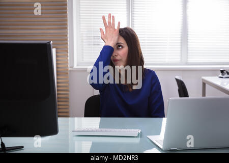 Sad Young Businesswoman With Her Hand On Forehead Sitting In Office Stock Photo