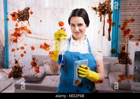 Smiling Female Janitor Cleaning Dirty Glass Window With Spray Stock Photo