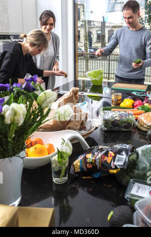 Group of friends casually snacking on a selection of food while laughing and enjoying themselves. Stock Photo