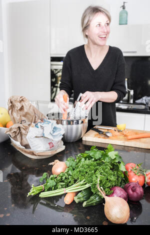 Selective focus -Fresh herbs and vegetables on the kitchen counter.Group of friends cooking together while laughing and enjoying themselves. Stock Photo