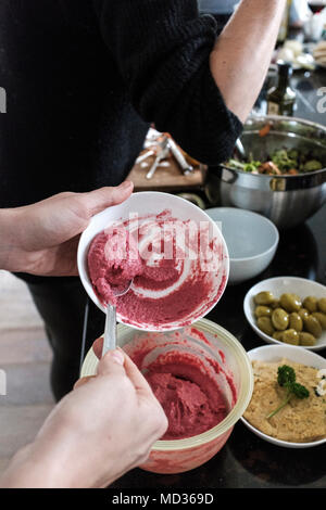 Woman preparing beetroot hummus and selection of vegetarian platers-mixed salad,green olive,hummus classic. Stock Photo