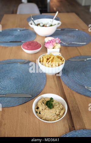 Table with vegetarian snacks-hummus classic,tortilla chips,beetroot hummus,greek salad Stock Photo