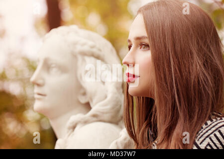 Autumn Portrait of Pretty Woman and Marble Statue Outdoors. Profile Stock Photo