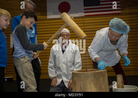 Japanese American Society volunteers assist American children with Mochitsuki, or rice pounding, to make mochi during the 61st Iwakuni Annual Culture Festival in Iwakuni City, Japan, March 17, 2018. The festival showcased many traditional Japanese cultural activities and performances. The event was held off base this year with support from Iwakuni City, which allowed more Iwakuni residents to come together with the base community. (U.S. Marine Corps photo by Lance Cpl. Lauren Brune) Stock Photo
