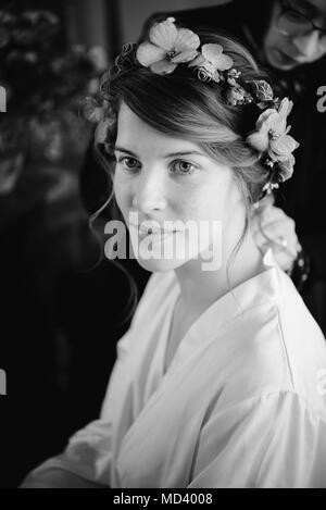 Bride preparing for wedding, hairstylist in background Stock Photo