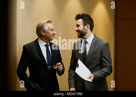 Two businessmen talking in office corridor Stock Photo