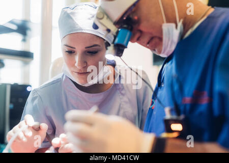 Dentist and dental nurse using dental equipment Stock Photo