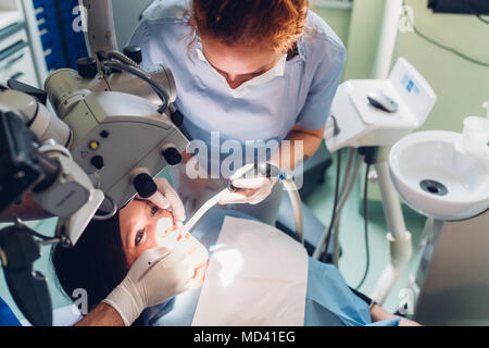 Dentist and dental nurse carrying out dental procedure on female patient Stock Photo