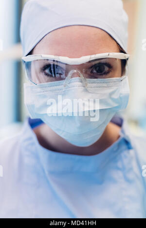 Portrait of female dentist, wearing surgical mask and protective eyewear, close-up Stock Photo