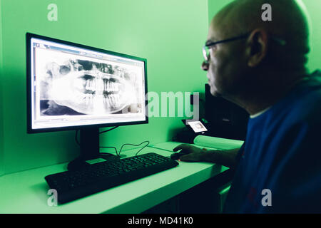 Dentist looking at dental x-ray on computer Stock Photo