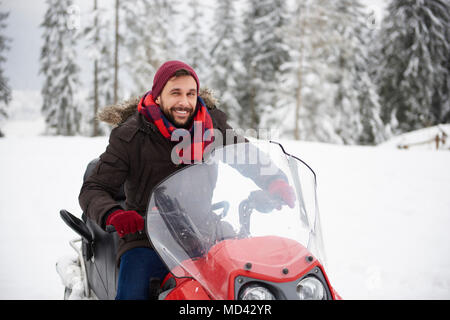 Young man riding snowmobile in winter Stock Photo