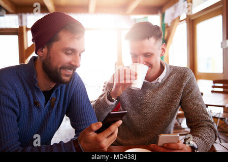 Young men smiling over text message on mobile phones Stock Photo