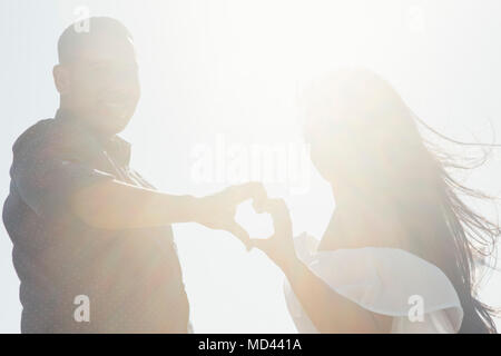 Portrait of couple outdoors, hands touching, making heart shape Stock Photo