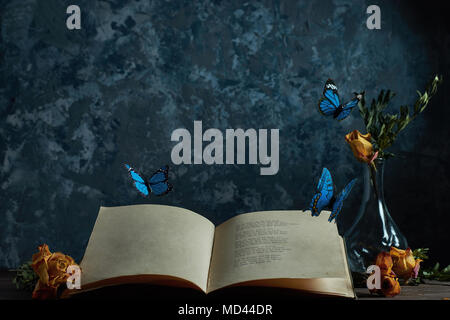 Still life an open book on the table a vase with flowers flying butterflies, a place for your text Stock Photo