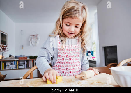 Young girl making cookies, using cookie cutter Stock Photo
