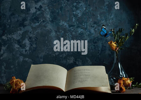 Still life an open book on the table a vase with flowers flying butterflies, a place for your text Stock Photo