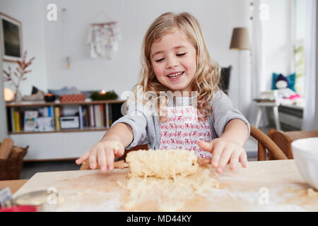 Young girl rolling out cookie dough, dough stuck to rolling pin Stock Photo