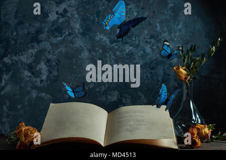 Still life an open book on the table a vase with flowers flying butterflies, a place for your text Stock Photo