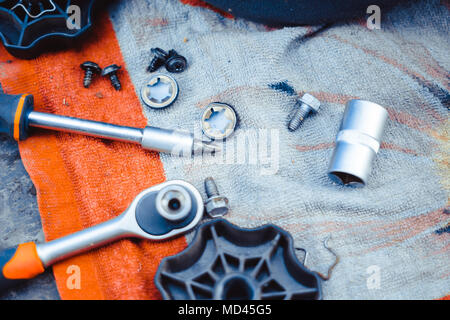 Car workshop tools left lying around on the floor. Workshop floor greasy and dirty. Stock Photo