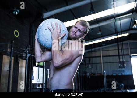 Man exercising in gymnasium, using atlas stone Stock Photo