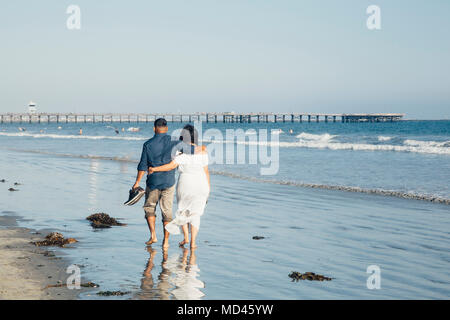 Couple walking along beach, barefoot, rear view, Seal Beach, California, USA Stock Photo