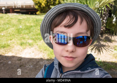 A young boy wearing sunglasses poses for a photograph. Stock Photo
