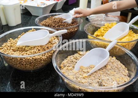 A selection of breakfast cereals with plastic scoops at a self service breakfast buffet in a hotel restaurant. Stock Photo
