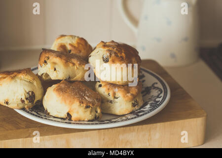 Home made Fruit Scones on a patterned plate with a jug in the background Stock Photo