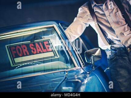 Men Putting For Sale Sign Under His Car Windshield. Selling Car Theme. Stock Photo