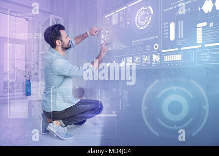 Attentive programmer changing setting in his program while working at home Stock Photo