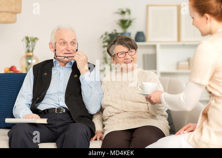 Elderly couple having a tea with a nurse during a home visit Stock Photo