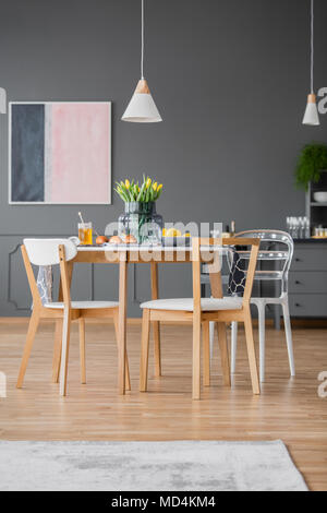 Creative design modern dining chairs around a simple kitchen table with a tablecloth in a gray open space apartment interior Stock Photo