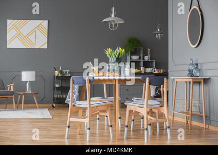 Stylish gray apartment interior with hardwood floors, molding and an open dining and living room space with wooden furniture Stock Photo