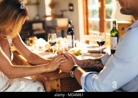 Close up of couple in love holding hands at home sitting at kitchen dining table. Close up of man and woman having romantic meal at home. Stock Photo