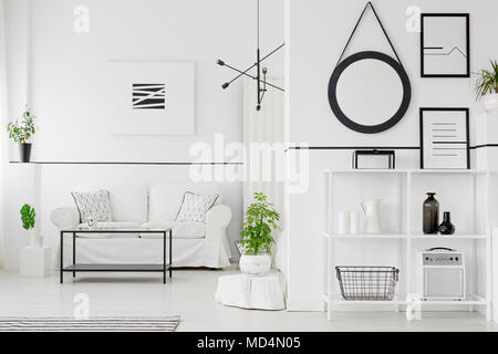 Black and white living room interior with couch, table, shelves, ornaments, posters and plants Stock Photo