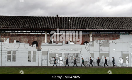 Artist Mick Peter(L) alongside members of the public as they walk past 'Regenerators', an 80-metre long billboard piece in Glasgow which covers the empty facade of an historic former gas purifying shed which is part of the Glasgow International Festival of Visual Art. Stock Photo
