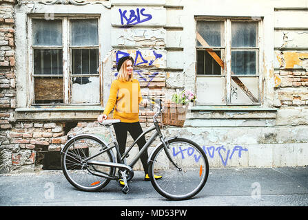Young woman with bicycle in sunny spring town. Stock Photo