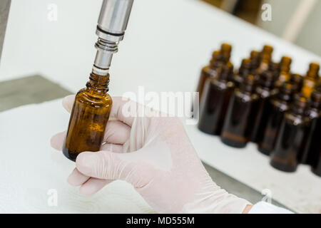 Close up of female lab worker hand with gloves filling the bottle with syrup. Stock Photo