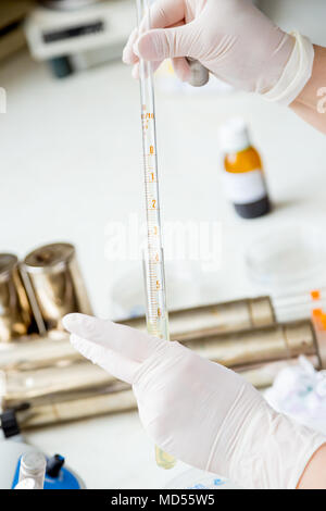 Female scientist worker hands holding glass measuring pipette in laboratory. Stock Photo