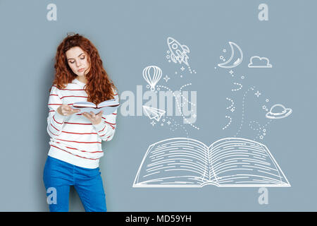 Young teacher looking interested while reading a book Stock Photo