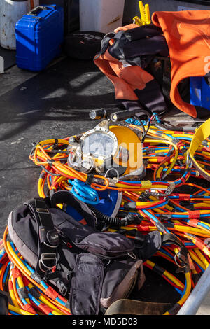Professional diver's full faced helmet, with hookah and communication cables, on the deck of a boat Stock Photo