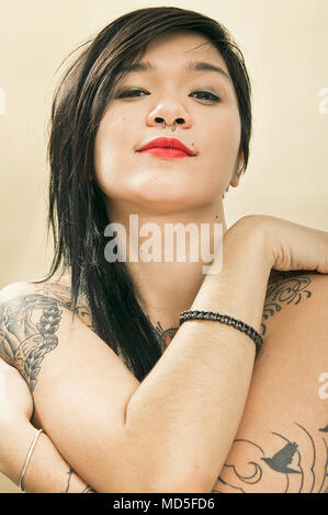 A portrait of a young Japanese woman who has some unidentifiable tattoos. Stock Photo