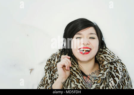 A young Japanese woman smoking a cigarette laying in the snow. Stock Photo