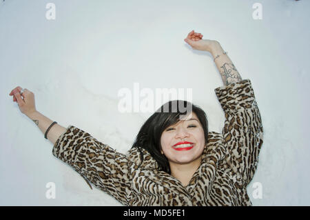 A woman laying down in the snow smiling. Stock Photo