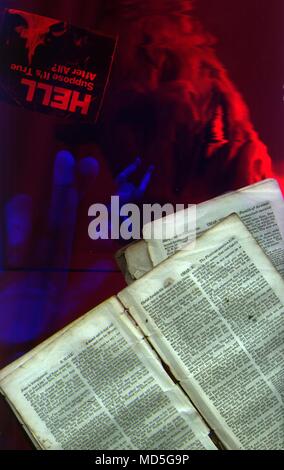 Demon Hand Scriptures Pages from Bible. Demon face, doll and human hand Stock Photo - Alamy