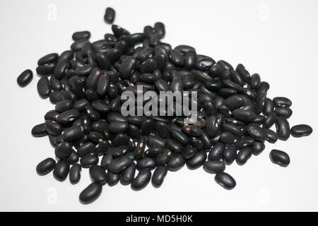 Pile of fresh raw uncooked black beans on white table background. Top view isolated. Stock Photo