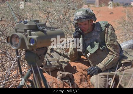 Pfc. Kaleb Bishop, a fire support specialist with 2nd Battery, 3rd Field Artillery Regiment, 1st Armored Division Artillery, communicates a situation report after scanning his sector with a Lightweight Laser Designator Rangefinder at the Combined Arms Collective Training Facility, Orogrande, N.M., March 22, 2018. Bishop’s unit took the role of opposing force in Iron Focus 18.1, a major training event in which various units of Fort Bliss took part of. (U.S. Army photo by Sgt. Kris Bonet) Stock Photo